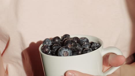 woman eating blueberries from a cup