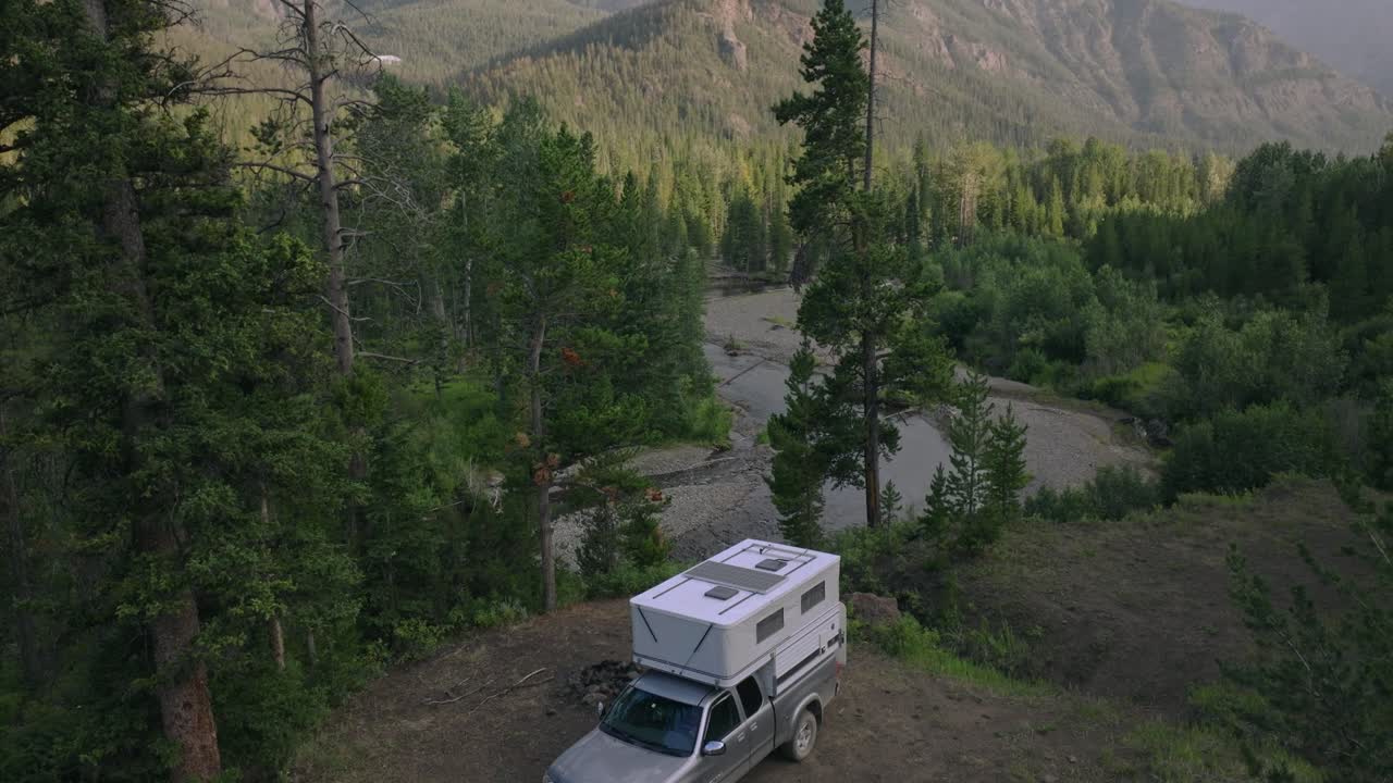 Aerial ascend above campsite in Sunlight Basin, Wyoming, showing the truck camper surrounded by nature and trees