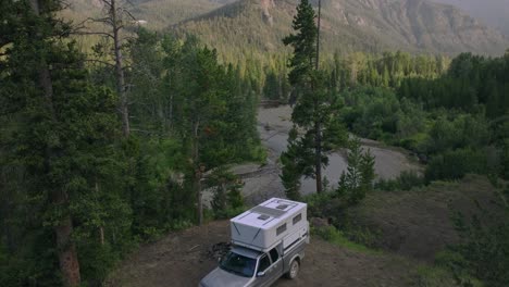 aerial ascend above campsite in sunlight basin, wyoming, showing the truck camper surrounded by nature and trees