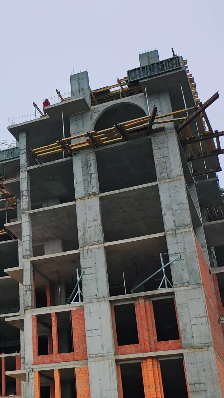 Construction of high-rise building. Front view of huge building in the process of construction. New construction site in the city. Vertical video