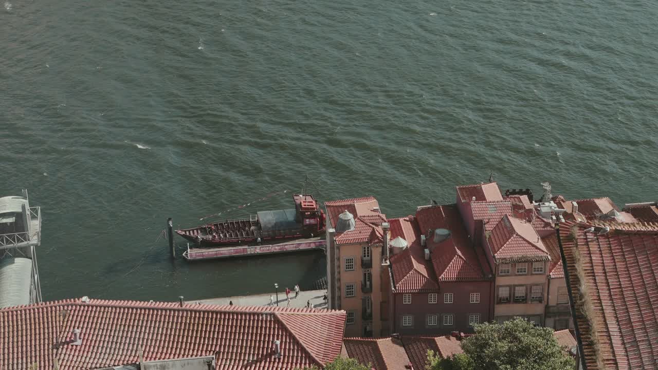 traditional wooden boat rests beside terracotta rooftops along the Douro River in Porto Portugal, capturing the charm of riverside life