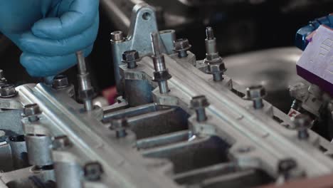 a mechanic hand tightening engine bolts with blue latex disposable gloves