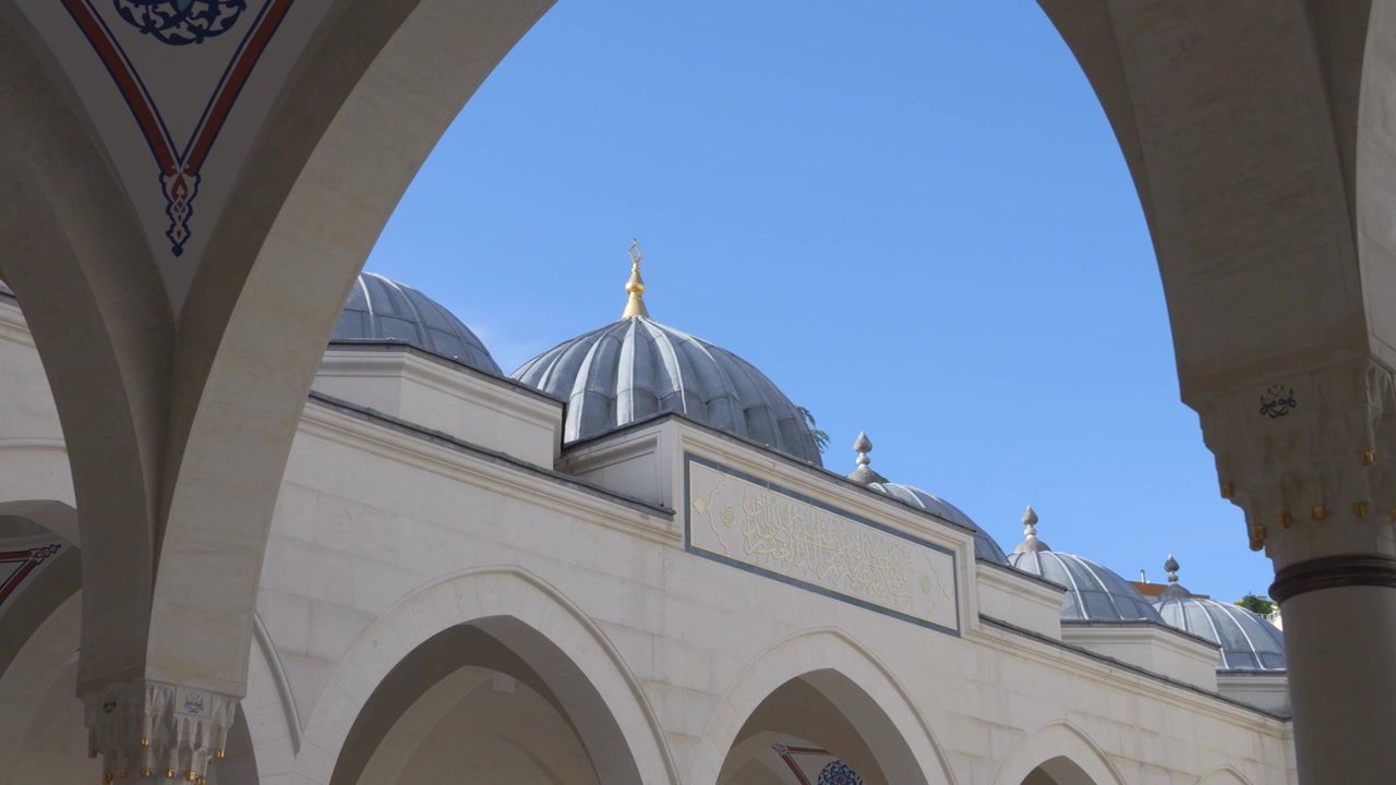 Cupole di piombo e pinnacolo dorato della Moschea Namazgah visti attraverso un arco del cortile a Tirana, Albania.