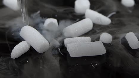 dry ice on dark surface onto which water drips and it's chemical reaction produced smokes. slow