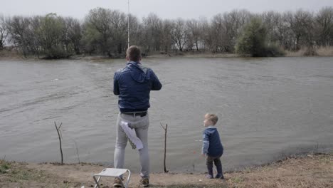 fisherman spinning fishing reel during biting in river. father fishing with son