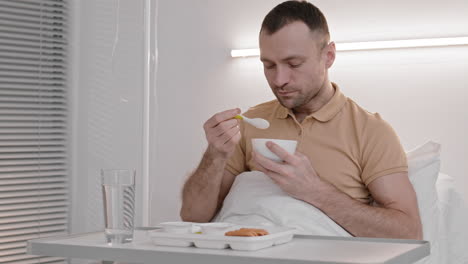hombre comiendo en una cama de hospital