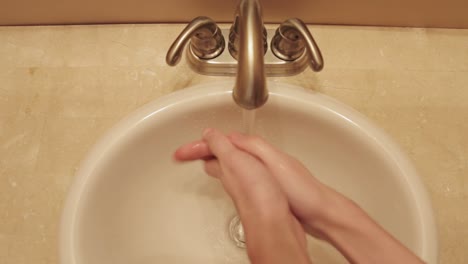 top down shot of hands being washed under a bathroom sink