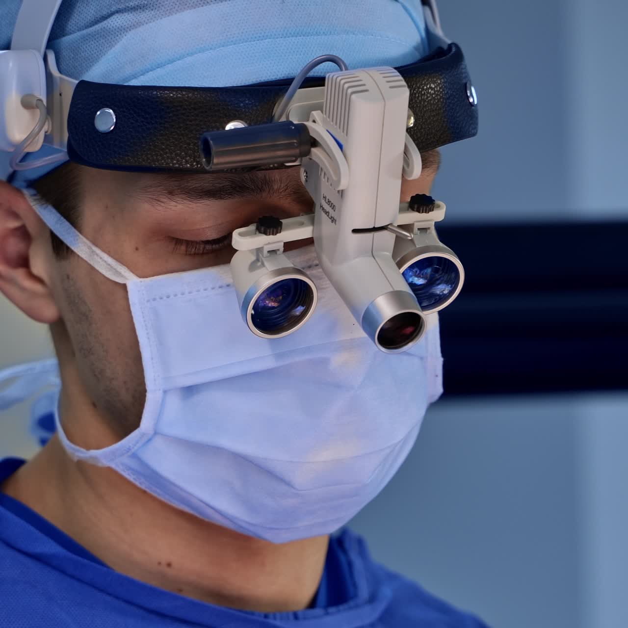 Mid-aged male surgeon in mask and device glasses at surgery. Portrait of a tired doctor yawning. Close up