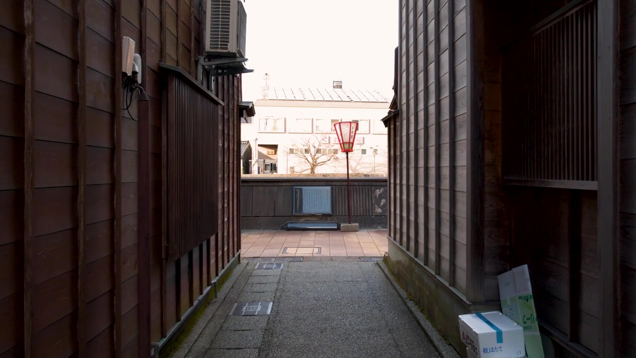 Slow forward camera movement moving through a narrow historic wooden alley in Kanazawa, Japan.