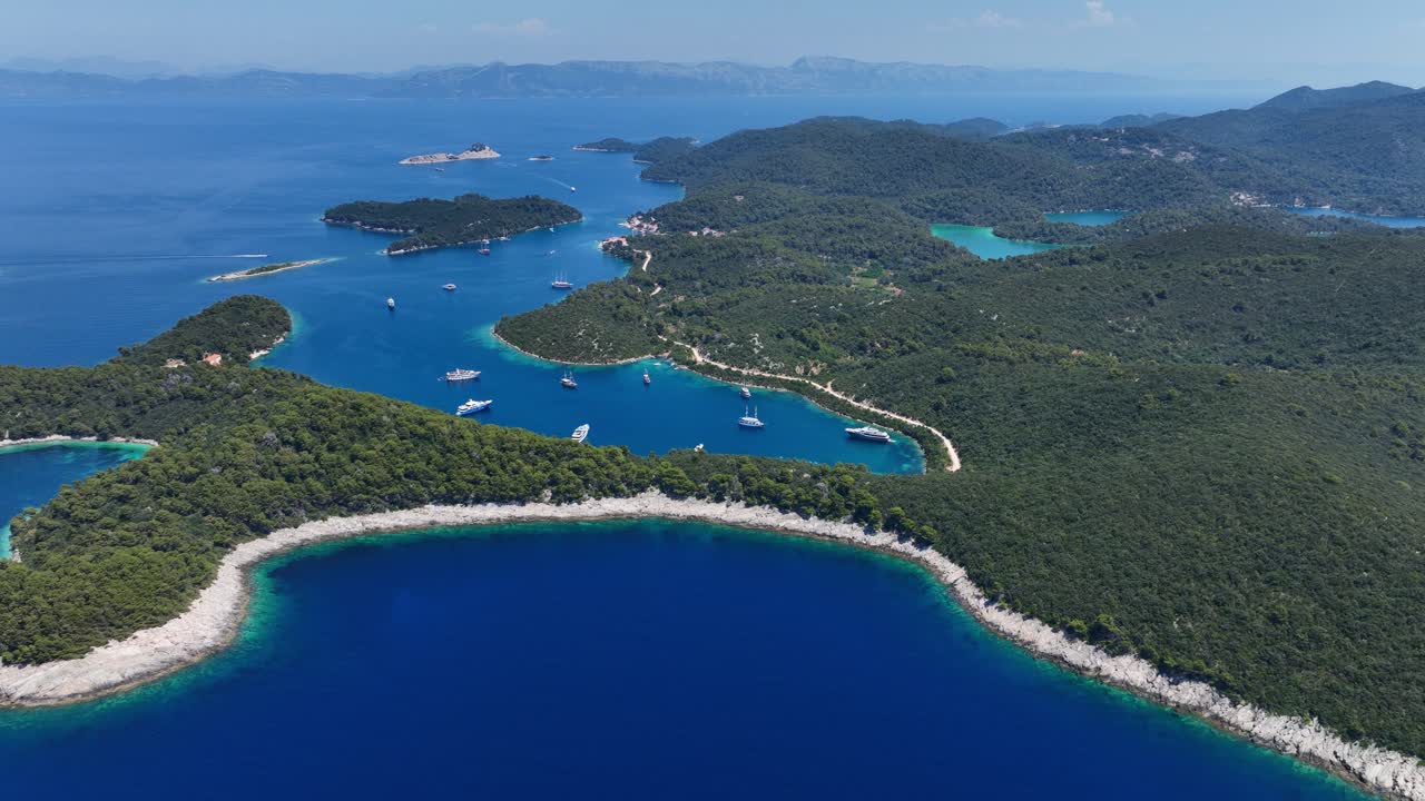Seascape of Mljet island with yachts anchored in calm blue bays, aerial pan