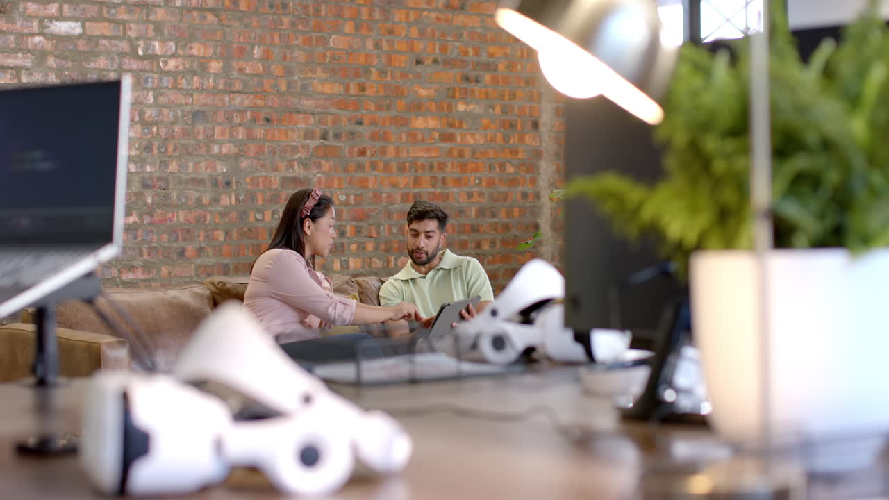 Collaborating on project, colleagues using laptop in modern office with VR headsets