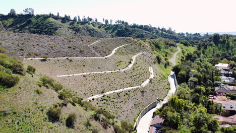 Low-aerial-shot-of-winding-road-and-mansions-along-hillside-in-Beverly-Hills,-California,-USA-at-daytime