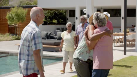 happy diverse senior friends talking and embracing at sunny garden party, unaltered, in slow motion