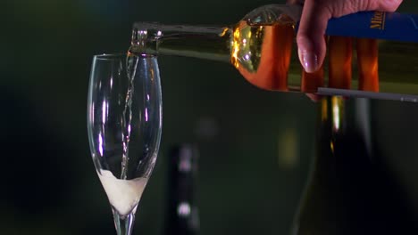 a slow pour of white sparkling wine from a bottle with dark background