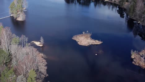 Drone-shot-orbiting-over-small-island-in-lake-in-Sweden-during-day