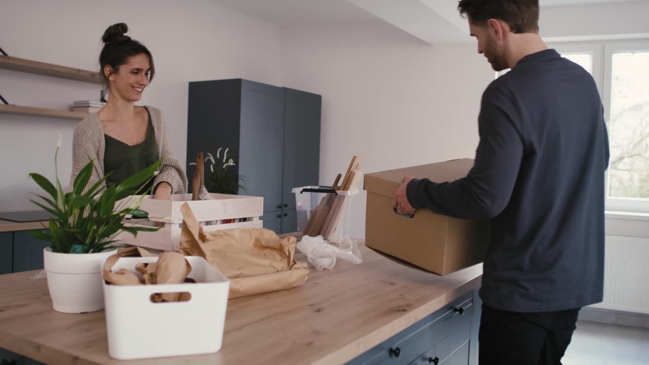 una pareja caucásica ocupada desempaquetando algunas cosas de cocina en su nueva casa.