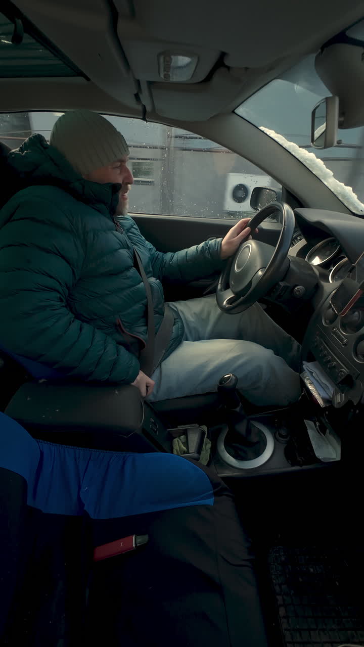 Vertikalt innvendig sidebilde av en mann som fester sikkerhetsbeltet mens han kjører på en kald vintervei. Egnet for temaer om trafikksikkerhet og daglig transport