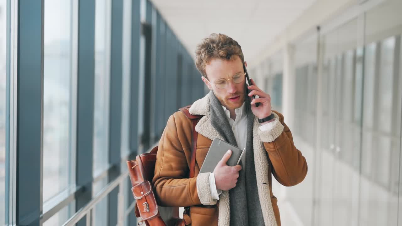 agradable joven adulto caminando por el pasillo hablando por teléfono