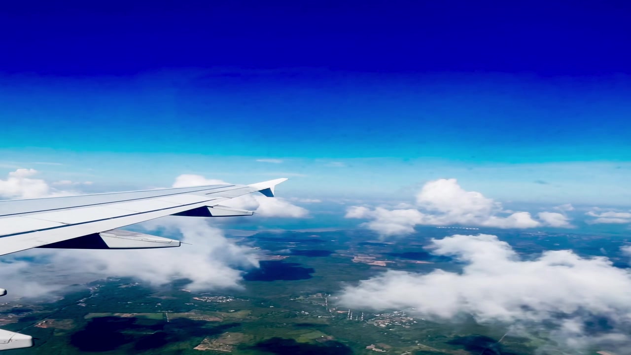 Vista aerea dell'ala di un aereo sopra nuvole e paesaggio