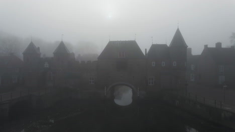 jib up of medieval gate over river with thick fog in the background