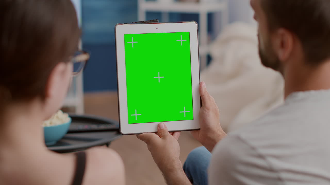 Closeup of couple holding vertical digital tablet with green screen in online conference or group video call