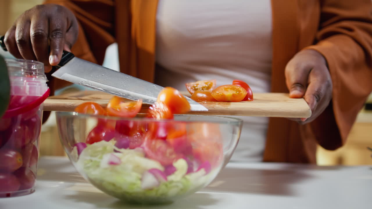 Food vlogger che taglia pomodorini, ricetta insalata al bancone.