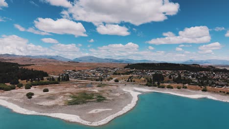 aerial approaching shot of lake tekapo town in new zealand with beautiful landscape in summer