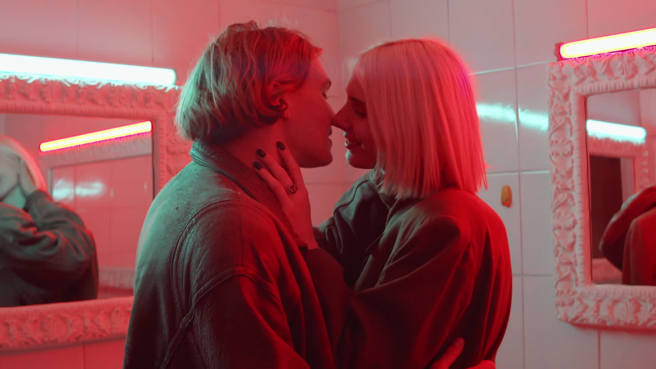 Coppia sensuale che si bacia in una stanza con luce al neon rossa