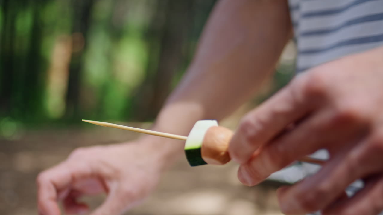 Man hands preparing vegetable skewer in forest picnic closeup. Unknown guy