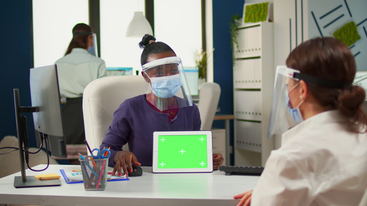 Black woman showing to manager tablet with green screen