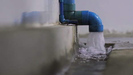 heavy rain causes a strong water flow out of a blue waste pipe