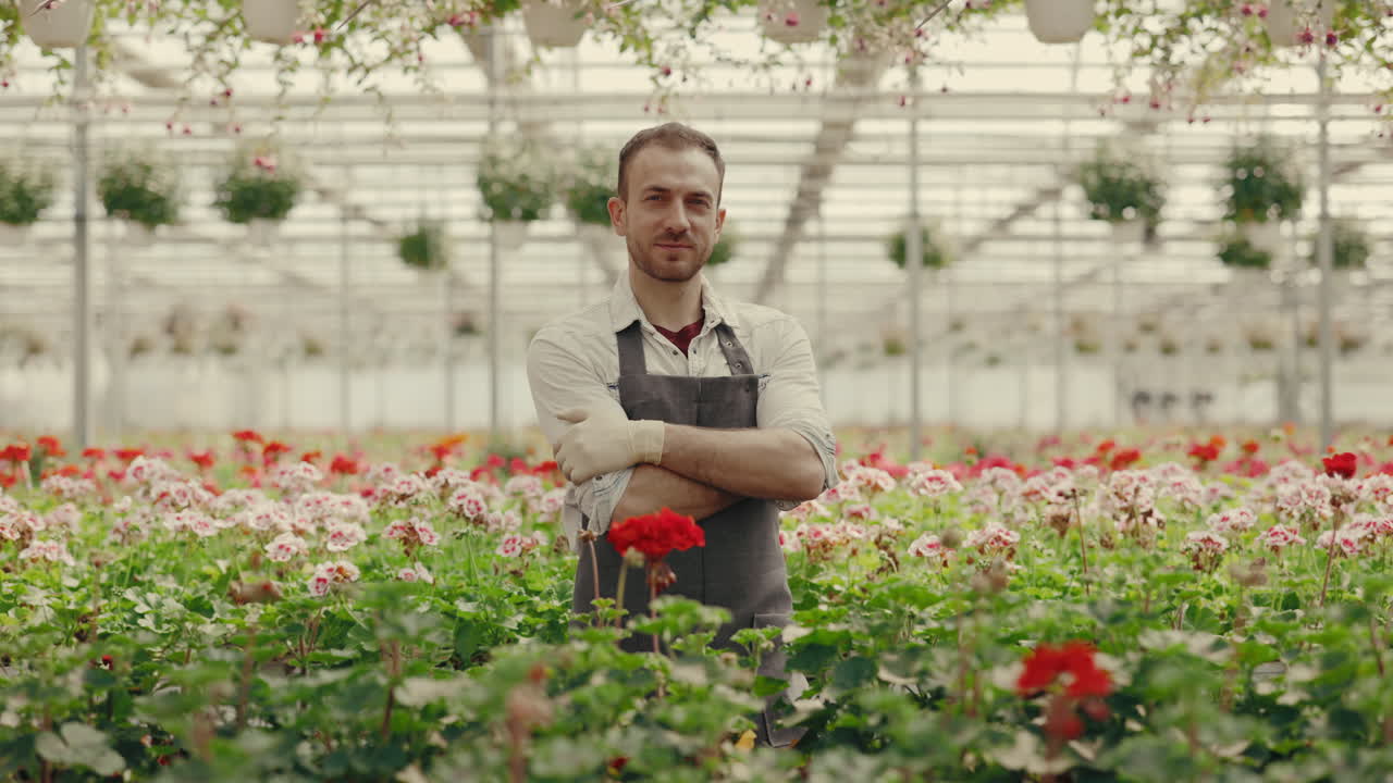 Giardiniere professionista in piedi in una serra vivace piena di fiori in fiore.
