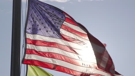 an american flag blowing in the wind, backlit by the sun