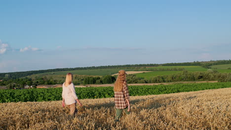 mom and teenage daughter walking through a picturesque wheat field