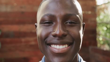 Retrato-De-Un-Feliz-Hombre-Afroamericano-Sonriendo-En-Una-Terraza-Al-Aire-Libre,-Cámara-Lenta