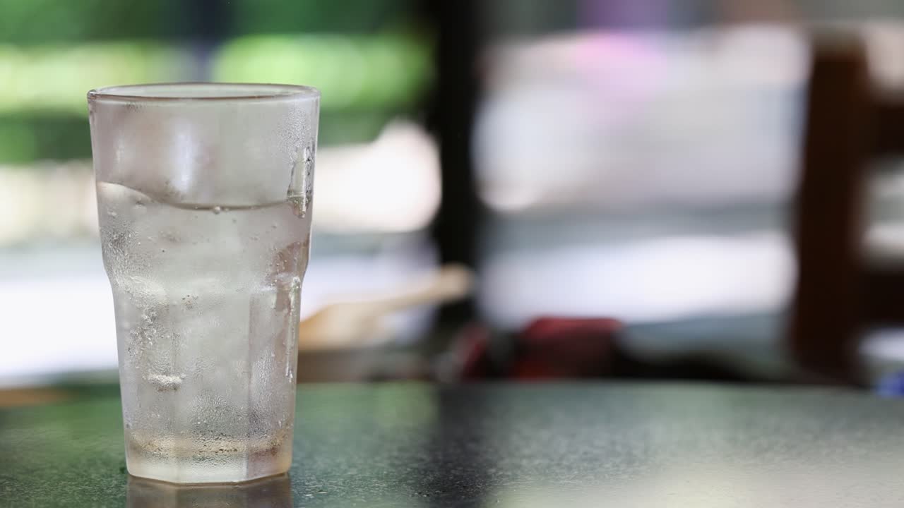 응축물 이 있는 차가운 물 한 잔 이 테이블 위 에 놓여 있어, 밝은 환경 에서 상쾌 한 시원 함 을 강조 한다