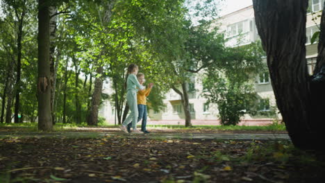 young boy and girl walking together on park path near residential apartment building, surrounded by trees and nature, enjoying relaxed moment while talking and interacting in peaceful neighborhood