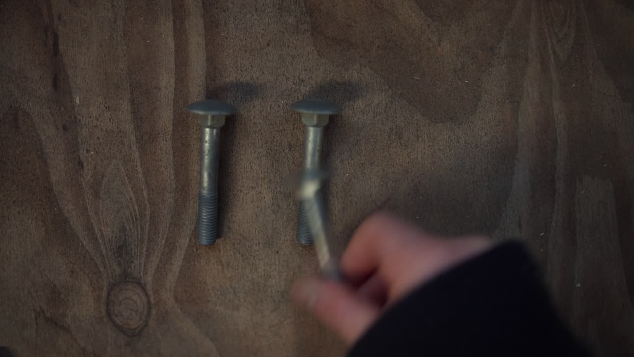 A Man's Hand is Placing Nuts and Bolts on the Surface of the Table in Indre Fosen, Trondelag County, Norway - Close Up