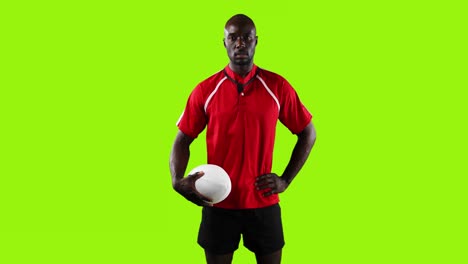 professional rugby player standing and holding a ball on green background 4k