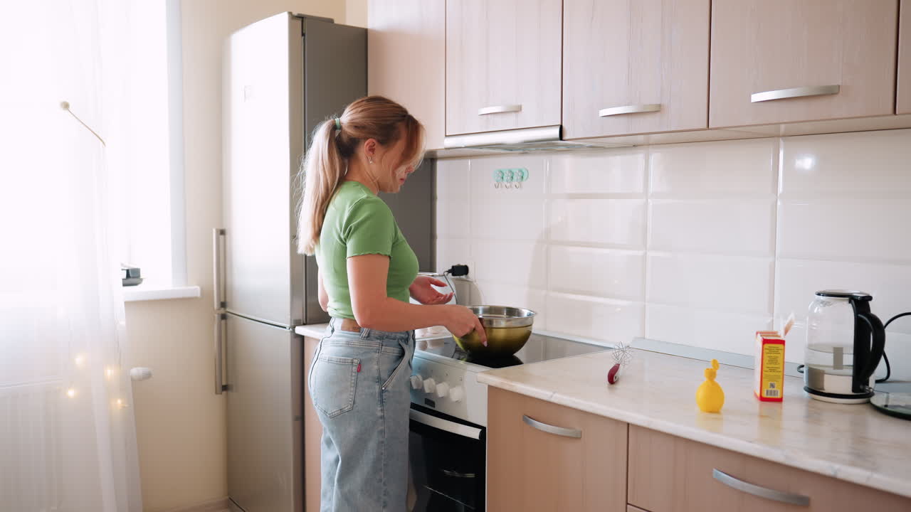 Casalinga vista da dietro che cammina in cucina verso la ciotola sul fornello con una luce decorativa che lampeggia nella tenda, creando una calda scena domestica di cucina quotidiana e routine familiare
