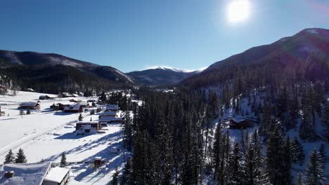 drone aerial view of snow covered homes in a valley with mountains