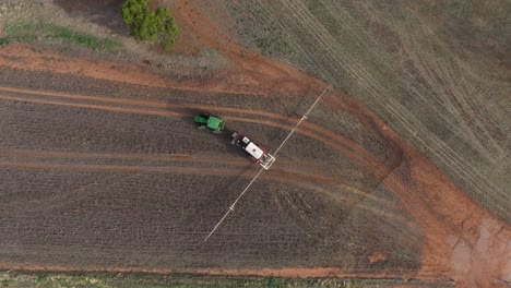 top-down birds eye view of farming tractor driving across empty field