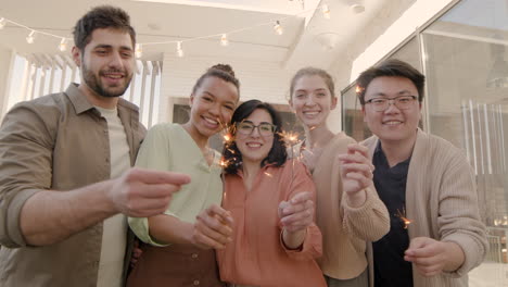 un gruppo multietnico di amici che guardano la telecamera, sorridendo e agitando delle stelle filanti 1