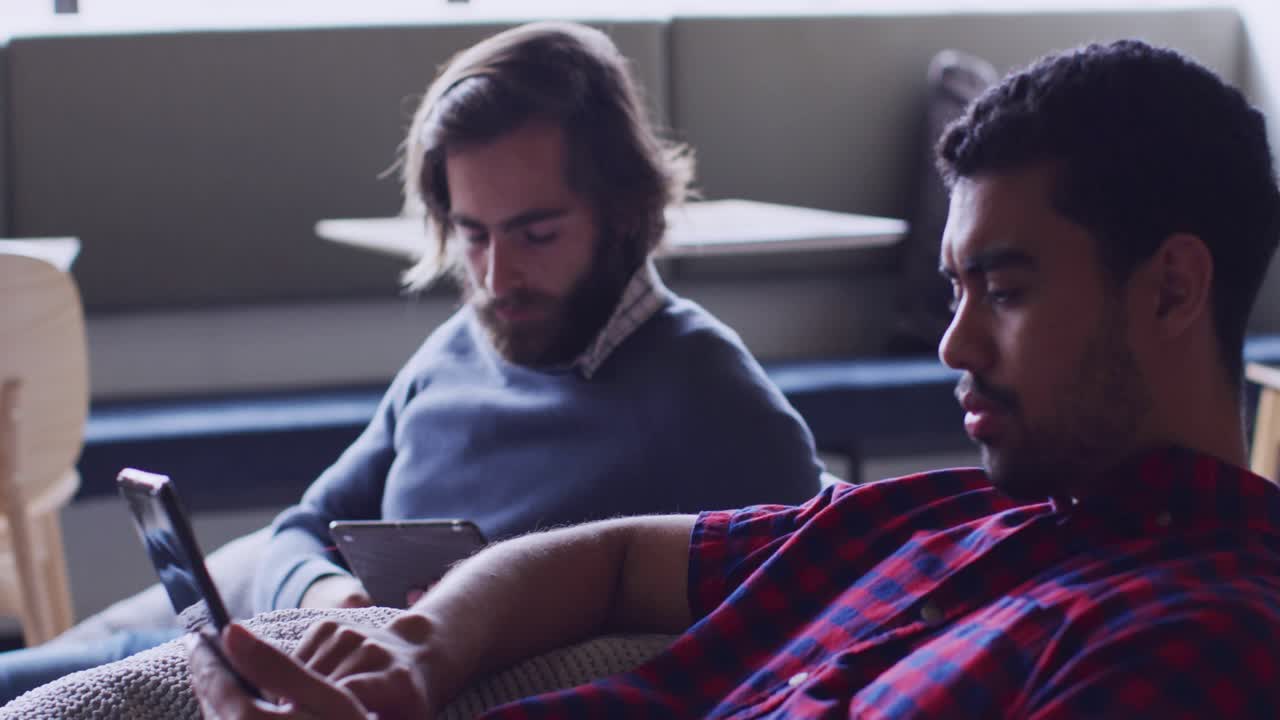 Dois homens usando um celular e um tablet no sofá, gerando selos de interface de usuário de redes sociais animados e discutindo conteúdo