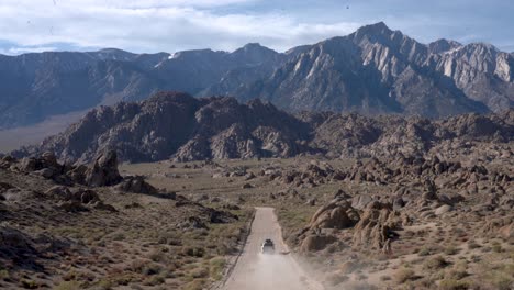 white off-road suv driving away on a dirt road, towards the eastern sierra mountains, in the desert