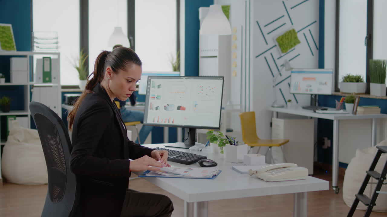 Businesswoman working with computer and data charts on paper