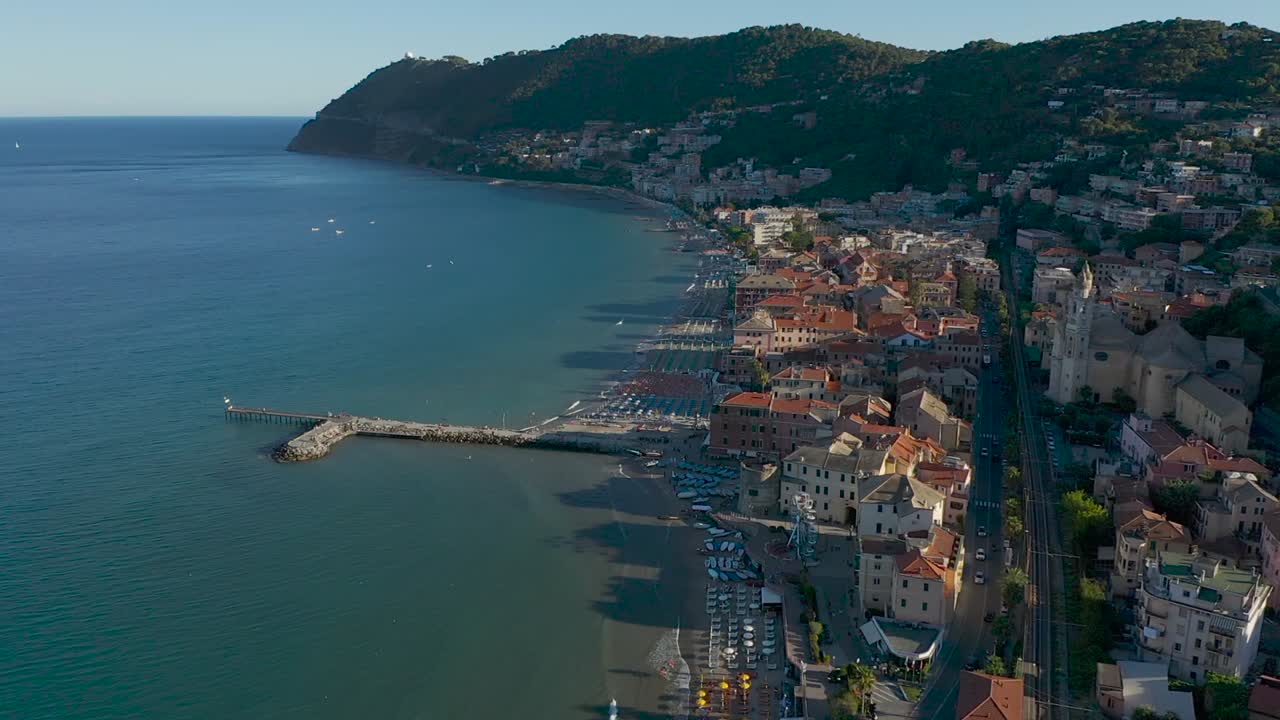 Drone che vola all'indietro dalla città di Laigueglia, Liguria, durante il tramonto