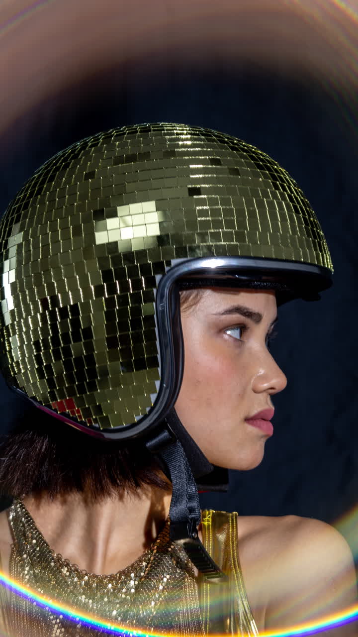 Mulher bonita em festa posa sentada em sofá vermelho com capacete de bola de discoteca dourado, vertical