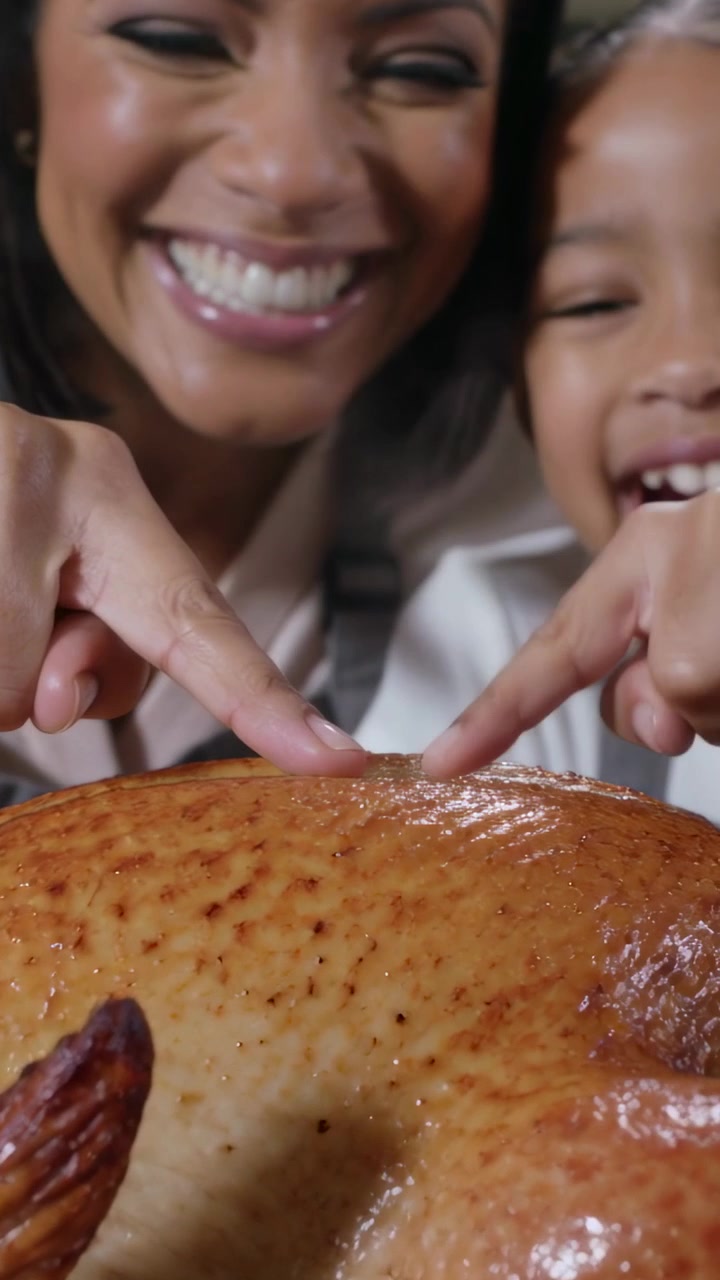Vidéo verticale : Dinde rôtie, maman et fille pressant la peau pour la rendre croustillante au comptoir, tabliers.