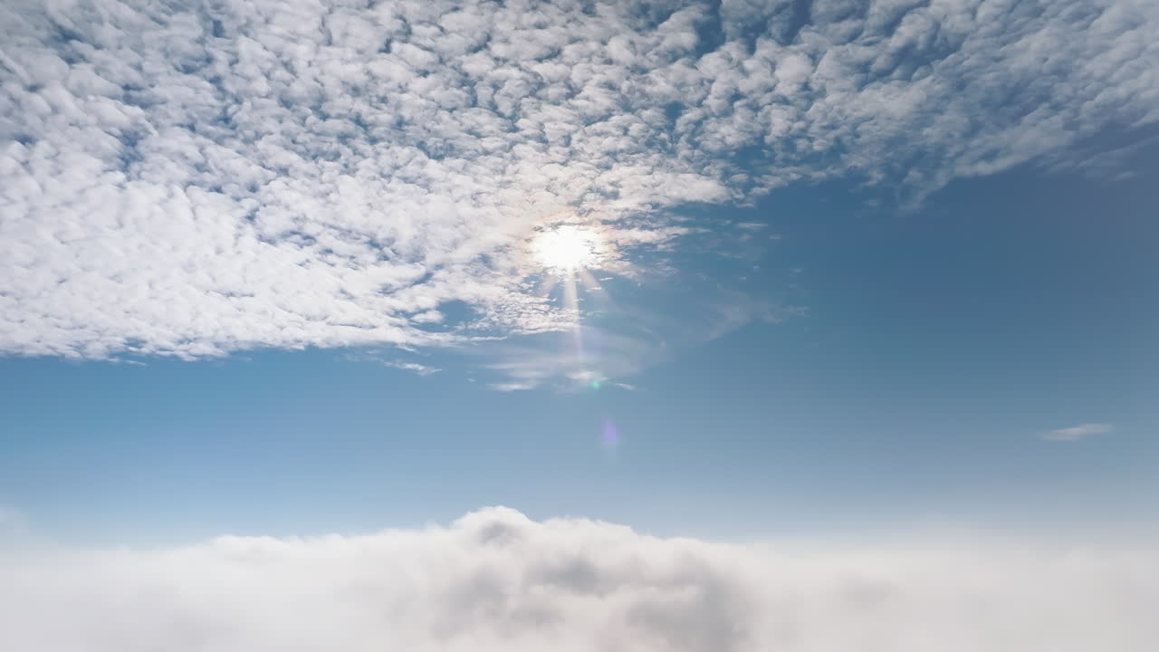 Aerial drone view of the sky with clouds and bright sun